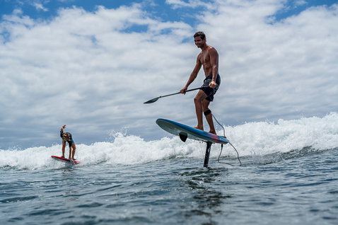 Duotone Sky SUP planche de foil lors du foiling sur une vague océanique avec deux athlètes