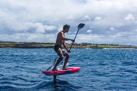 Planche de foil SUP Duotone Fanatic Downwinder lors du foiling en downwind sur l'océan en corail et blanc
