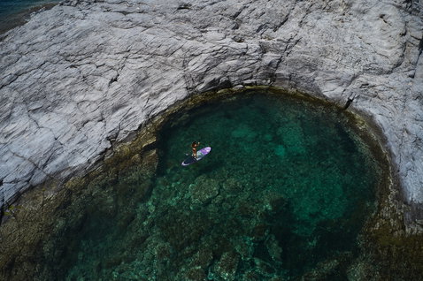 Planche SUP Duotone Diamond lors d'une session de paddle dans une crique rocheuse turquoise en Sardaigne