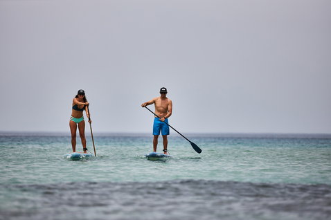 Planche SUP Duotone Ray Pure Light lors d'une session de stand-up paddle sur océan calme avec deux riders