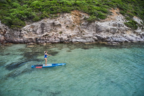 Planche SUP composite Duotone Ray Pure 12'6" lors d'une session de paddle côtier en Sardaigne en bleu et rouge