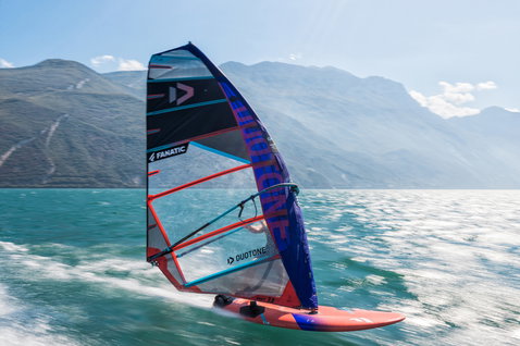Fanatic Falcon Slalom TE race windsurf board during windsurfing on an alpine lake in red and orange