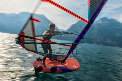 Fanatic Falcon Foil TE windsurf foil board during foiling on an alpine lake with mountain backdrop