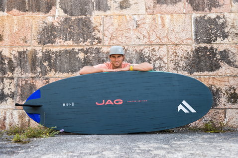 Fanatic Jag Limited Edition windsurf board in dark slate blue with carbon deck against stone wall