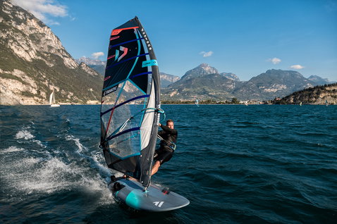 Fanatic Jag LTD race windsurf board during windsurfing on an alpine lake with mountain backdrop