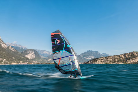 Fanatic Jag LTD windsurf race board during windsurfing on an alpine lake with mountain backdrop