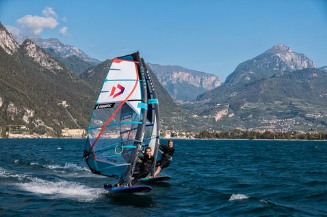 Fanatic Blast LTD freeride windsurf board during windsurfing on an alpine lake with mountain backdrop