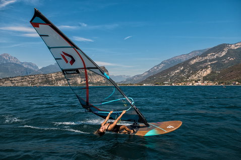 Fanatic Gecko Eco freeride windsurf board during windsurfing on Lake Garda with alpine backdrop