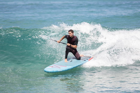 Duotone Fly Air iSUP Board beim SUP-Surfen in den Wellen auf dem Meer in hellblau