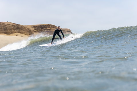 Duotone ProWave LTD SUP surfboard during wave riding on the ocean beside sandy cliffs