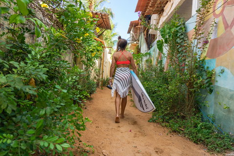Planche de SUP surf Duotone ProWave LTD transportée dans une ruelle tropicale ensoleillée