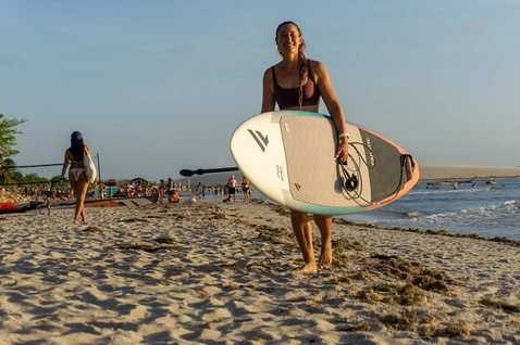 Planche de SUP vague Duotone ProWave LTD portée par une athlète sur une plage tropicale