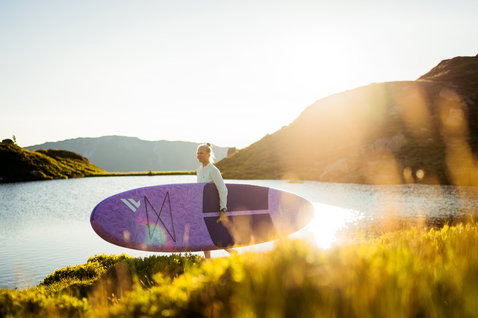 Duotone Diamond Air Pocket inflatable SUP board 10'4" in purple being carried at a mountain lake
