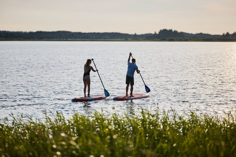 Duotone SUP Fly Air inflatable SUP board during flatwater paddling on a calm lake at golden hour