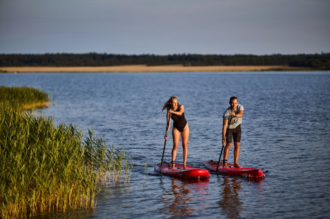 Duotone Fly Air inflatable SUP board during paddling on a calm lake at golden hour