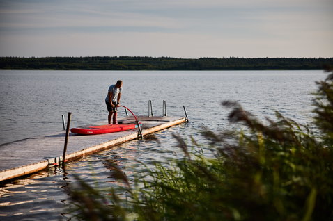 Duotone Fly Air inflatable SUP board in red being inflated on a lake dock in summer