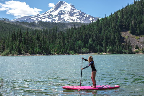 Duotone SUP Diamond Air inflatable SUP board in pink during stand-up paddling on a mountain lake