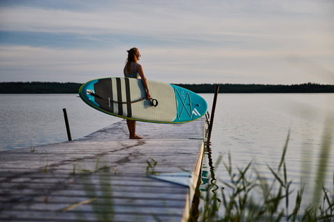 Duotone Fly Air aufblasbares SUP-Board in türkis und limetten-grün beim Stand-Up-Paddeln am See