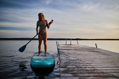 Duotone Fly Air Premium aufblasbares SUP Board beim Stand Up Paddeln auf einem ruhigen See im Abendlicht
