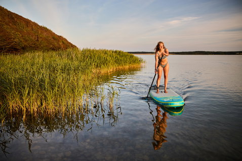 Duotone Fly Air Premium aufblasbares SUP Board beim Paddeln auf einem ruhigen See im Abendlicht