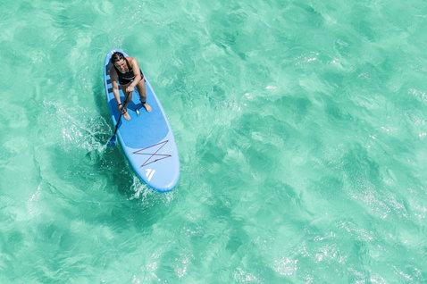 Duotone Fly Air inflatable SUP board during stand-up paddling on crystal-clear turquoise ocean water