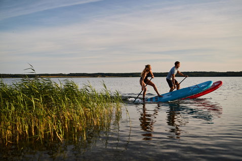Duotone Fly Air inflatable SUP board during stand up paddling on a calm lake at golden hour