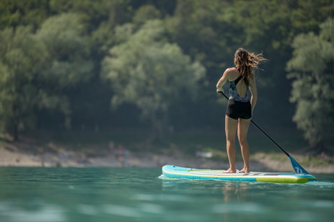 Duotone Ray Air Premium aufblasbares Touring-SUP beim Stand-Up-Paddeln auf einem ruhigen türkisen See