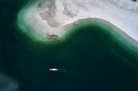 Fanatic Falcon Air Premium inflatable SUP raceboard during paddling on calm water beside a sandbar aerial view