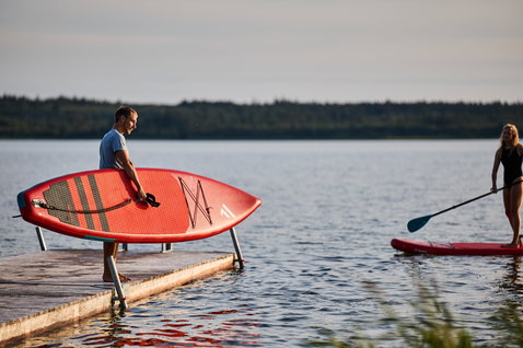 Duotone Ray Air aufblasbares Touring SUP Board in rot beim Stand Up Paddeln an einem See