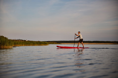Duotone Ray Air aufblasbares Touring-SUP beim Stand-Up-Paddling auf einem ruhigen Fluss im Abendlicht