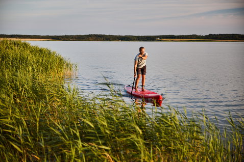 Duotone Ray Air aufblasbares Touring SUP Board beim Paddeln auf einem ruhigen See im Abendlicht