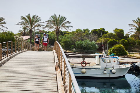 Fanatic Ray Air SLT iSUP package being carried along a Mediterranean marina pier in summer