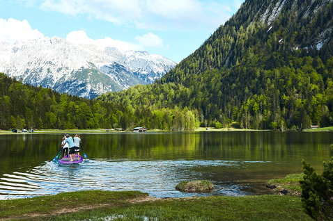 Fanatic Fly Air XL inflatable SUP board with group paddling on a calm alpine lake
