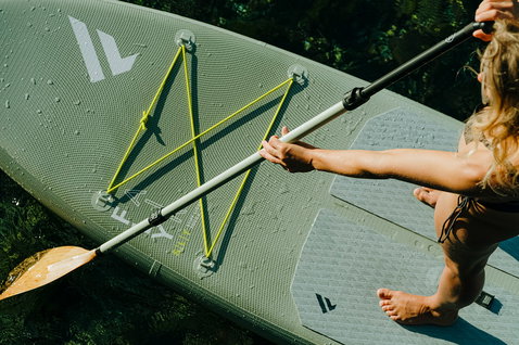 Fanatic Fly Air SLT inflatable SUP board in olive green with neon bungee cargo system during paddling