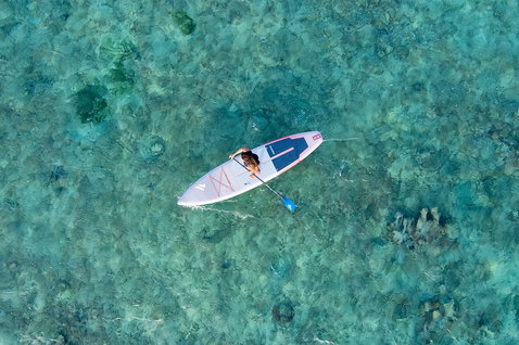 Fanatic Ray Air SLT inflatable SUP during paddling over turquoise tropical reef seen from aerial drone perspective