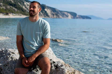 Fanatic SUP Tee unisex short-sleeve t-shirt in light blue worn at a rocky coastal beach