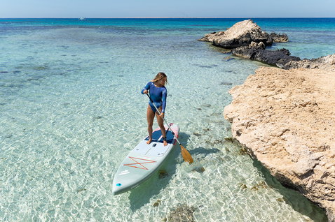 Fanatic Blitz Air SLT inflatable SUP board during stand up paddling in turquoise coastal water on a sunny day
